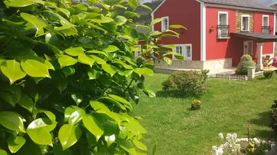 a red house with a yard with green grass at Vivienda de Uso Turístico Carballo Blanco 1 in Barral