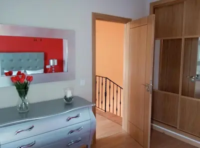 a room with a dresser with a vase of flowers on it at Vivienda de Uso Turístico Carballo Blanco 1 in Barral