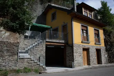 a yellow building with stairs and a garage at Casa Rural Las Mestas in Cangas del Narcea
