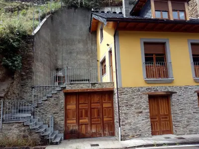 a building with two doors and stairs in front at Casa Rural Las Mestas in Cangas del Narcea