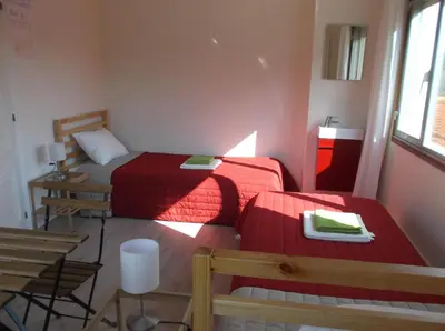 two beds in a small room with red sheets at O Cabalo Verde in Palas de Rei