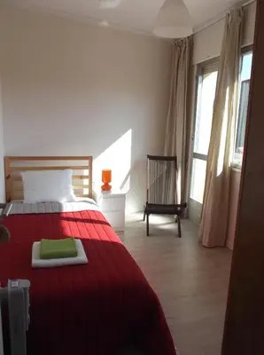 a bedroom with a red bed with a green blanket at O Cabalo Verde in Palas de Rei