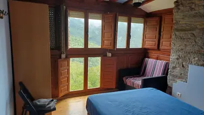 a bedroom with windows and a bed and a chair at A Palleira in Castro Caldelas