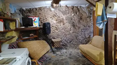 a room with two chairs and a stone wall at A Palleira in Castro Caldelas