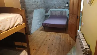 a hallway with a bed and a chair in a room at A Palleira in Castro Caldelas