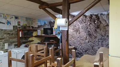 a room with chairs and a stone wall at A Palleira in Castro Caldelas