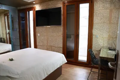 a bedroom with a bed and a desk and two windows at Casas Reais Boutique in Santiago de Compostela