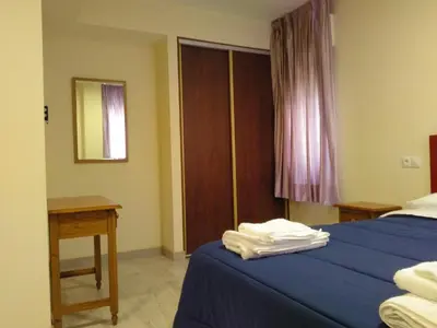 a bedroom with a blue bed with a table and a window at Hostal Orly in Camponaraya