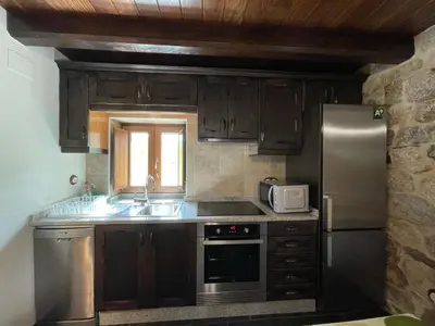 a kitchen with wooden cabinets and a stainless steel refrigerator at Casa Casoa in Piornedo