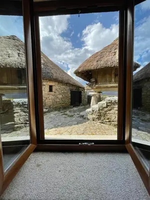 a window view of a building with a thatch roof at Casa Casoa in Piornedo