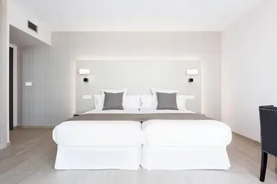 a white bedroom with a large white bed at Apartahotel A Cetárea in Burela de Cabo