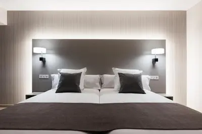 a bedroom with a large white bed with black pillows at Apartahotel A Cetárea in Burela de Cabo