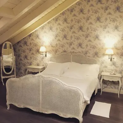 a bedroom with a white bed and floral wallpaper at Las Doñas del Portazgo in Villafranca del Bierzo