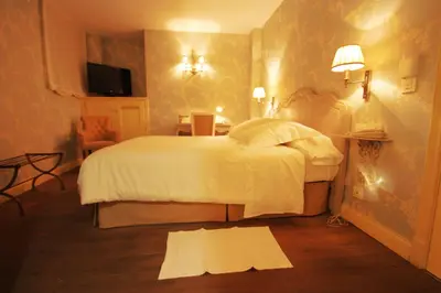 a bedroom with a white bed and a tv at Las Doñas del Portazgo in Villafranca del Bierzo