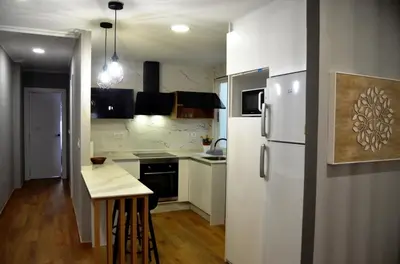 a kitchen with a white refrigerator and a table at REGO DA RAÑA APARTMENTS in Arzúa