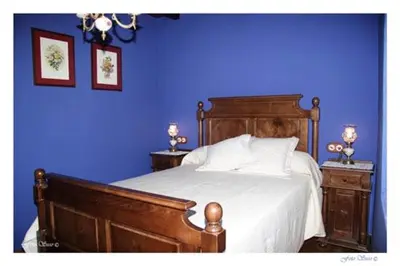 a bedroom with a wooden bed with a blue wall at Casa Rural Vila Pomar in Ribadeo