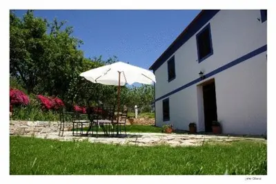 a table and chair under an umbrella next to a building at Casa Rural Vila Pomar in Ribadeo