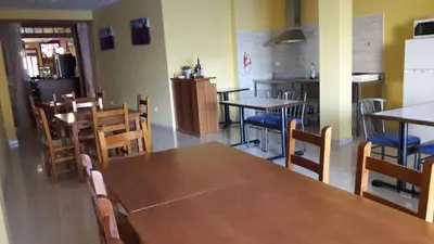 a dining room with tables and chairs and a kitchen at La Gallega in Cacabelos
