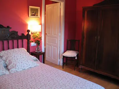 a bedroom with a bed with pink walls and a chair at Casa Rural Graña da Acea in Monfero