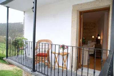 a balcony of a house with a chair and a table at Casa Rural Graña da Acea in Monfero