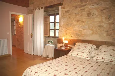 a bedroom with a bed and a stone wall at Casa Rural Graña da Acea in Monfero