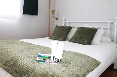 a white bed with a book on top of it at Apartamentos Castello in Cartavio