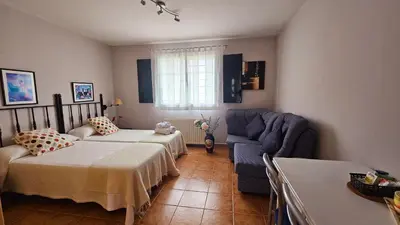 a bedroom with two beds and a blue couch at Apartamentos Castello in Cartavio