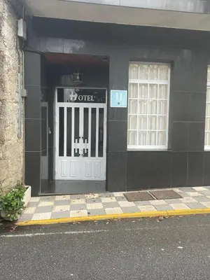 a black building with a door with a sign on it at Hotel Victorino in Silleda
