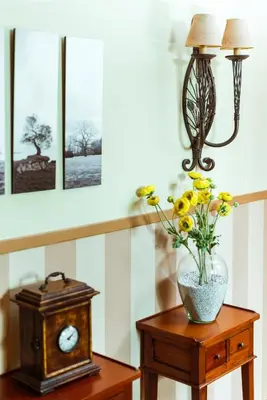 a table with a vase of flowers and a clock at El Tiempo Recobrado - Hotel de relax en El Bierzo in Villamartín de la Abadía