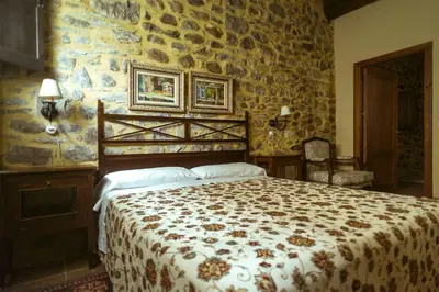 a bedroom with a bed and a stone wall at El Tiempo Recobrado - Hotel de relax en El Bierzo in Villamartín de la Abadía