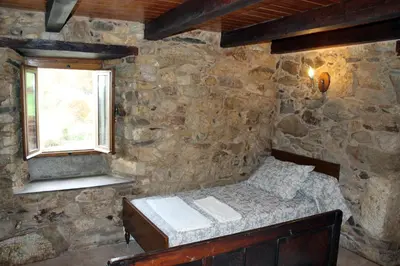 a bedroom with a bed in a stone wall at Casiña de Campo in Ferreiros