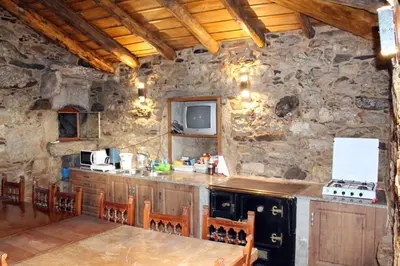 a kitchen with a stone wall with a counter and a table at Casiña de Campo in Ferreiros