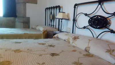 a bedroom with two beds and a table with a lamp at Casa Vixide in Lalín