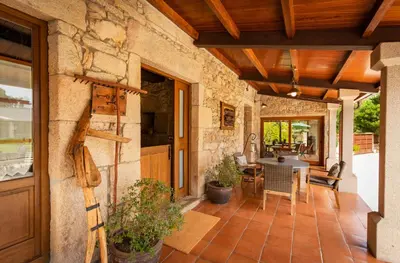 an outdoor patio with a stone wall and wooden ceiling at Casa do Mudo in Cervo