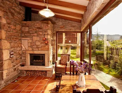 a living room with a stone fireplace and a table with flowers at Casa do Mudo in Cervo