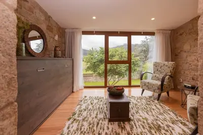 a living room with a large window and a chair at Casa do Mudo in Cervo