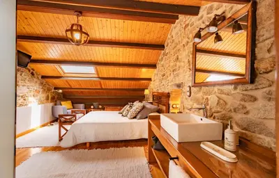 a bedroom with a bed and a stone wall at Casa do Mudo in Cervo