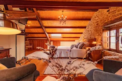 a bedroom with two beds and a stone wall at Casa do Mudo in Cervo