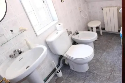 a white bathroom with a toilet and a sink at O Cruceiro in Puentedeume