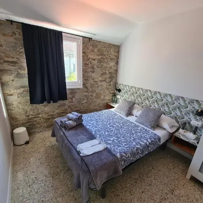 a bedroom with a bed with a blue comforter and a window at Pensión Casa Douro in Santiago de Compostela