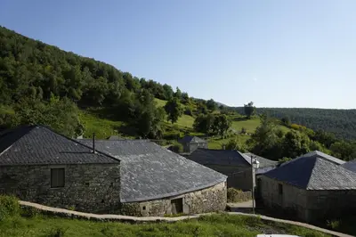 a group of stone buildings with a hill in the background at Vivienda Uso Turístico Prado novo in Suarbol
