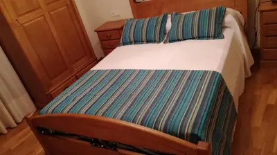 a bedroom with a bed with a striped sheet at Pension a Fontiña in Cuntis