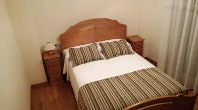 a bedroom with a large bed with a wooden headboard at Pension a Fontiña in Cuntis