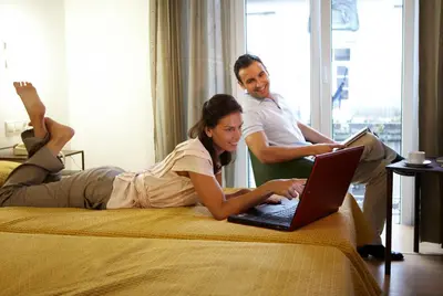 a woman laying on a bed with a laptop at Balneario Acuña in Caldas de Reis