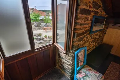 a room with a stone wall and a chair with a window at Casa do Conto in Doade