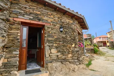 a stone house with a door and a stone wall at Casa do Conto in Doade