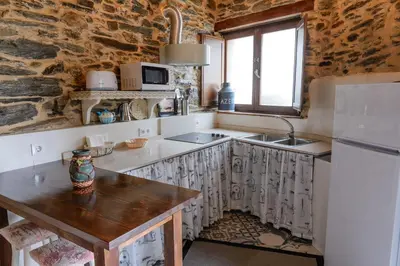 a kitchen with a wooden table and a refrigerator at Casa do Conto in Doade
