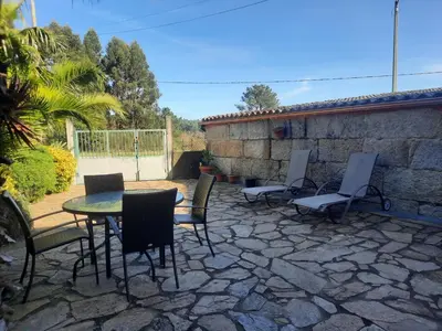 a patio with a table and chairs and a stone wall at Casa Rural Cabo de Aráns in Oroso