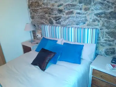 a bedroom with a white bed with blue pillows at Casa Rural Cabo de Aráns in Oroso