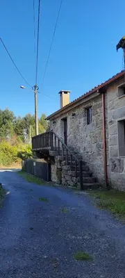 an old stone building with a staircase next to a street at Casa Rural Cabo de Aráns in Oroso